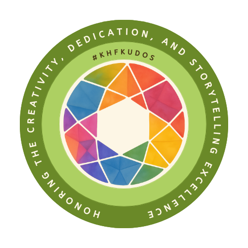 A circular badge design with a green outer ring. Inside the ring, white text reads: “HONORING THE CREATIVITY, DEDICATION, AND STORYTELLING EXCELLENCE.” At the top center, within the inner light green circle, is the text “#KHFkudos.” The center of the badge features a colorful kaleidoscope pattern made up of triangular segments in red, orange, yellow, green, blue, and purple, arranged around a central hexagon, the logo for Kaleidoscope Heritage Focus.